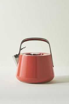 an orange kettle with a handle on a white surface