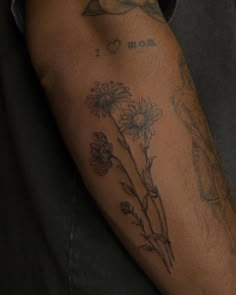 a man's arm with tattoos and flowers on it