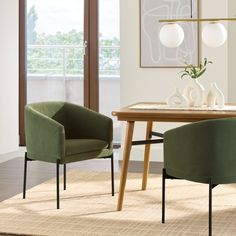 two green chairs sitting on top of a rug in front of a wooden dining table