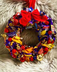 a candy wreath on top of a white fur covered floor with red bows and candies