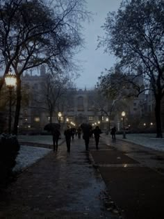 people walking down the street at night with umbrellas