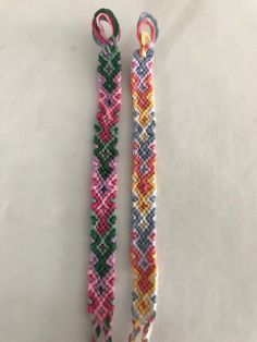 two bracelets made out of different colored seed beads on a white surface, one is pink and the other is green