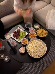 a table topped with bowls and plates filled with different types of food next to a couch