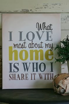 a potted plant sitting on top of a table next to a sign that says, what i love most about my home is who i share it with