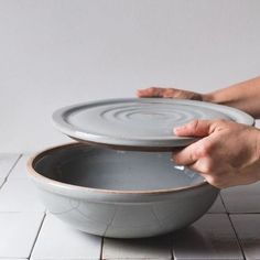 a person is holding two bowls in their hands on the floor, with one being lifted from the bowl