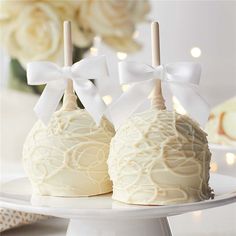 two white cake pops with bows on them