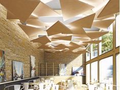 the interior of a restaurant with tables and chairs, hanging paper umbrellas over them