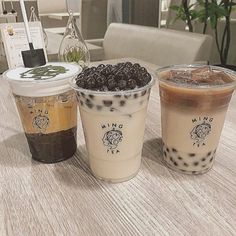 three cups of coffee sitting on top of a table next to each other with toppings