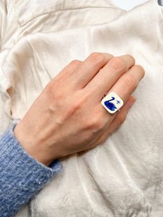 a woman's hand with a blue and white square shaped ring on her finger