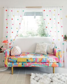 a brightly colored couch in front of a window with polka dots on the drapes