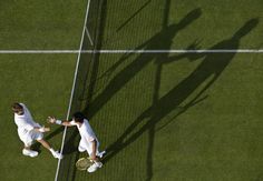 two tennis players are shaking hands on the grass court with their racquets