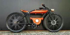 an orange and black bike parked next to a wall