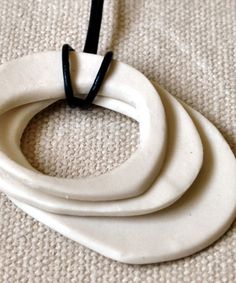 three white pieces of ceramic sitting on top of a cloth covered floor next to a black cord