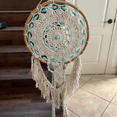 a white and blue dream catcher sitting on top of a wooden floor next to stairs