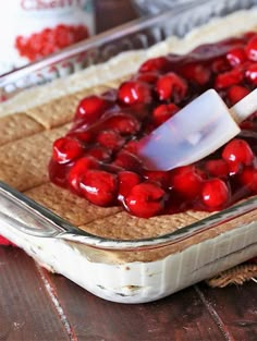 a cherry pie in a baking dish with a spatula scooping cherries into it