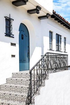 a white house with blue door and black iron handrails on the front steps