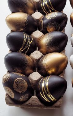 there are many different types of chocolate eggs in the carton, all decorated with gold and white designs