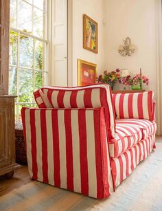 a red and white striped couch sitting in front of a window