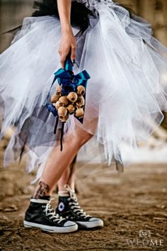 a woman in black and white dress holding a teddy bear with blue ribbon around her ankles