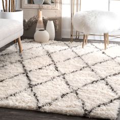 a white and black rug in a living room next to a mirror with vases on it