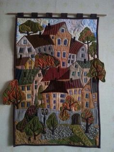 a wall hanging on the side of a building with trees and houses painted on it