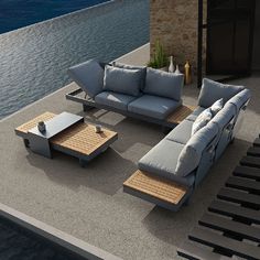 a couch and coffee table sitting on top of a concrete floor next to the ocean