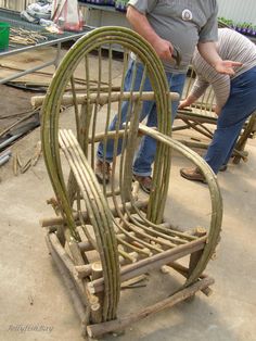 two people working on some kind of chair made out of sticks and wood planks