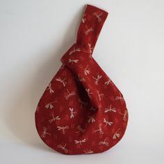 a red bag with dragonflies on it is hanging from the wall next to a white wall