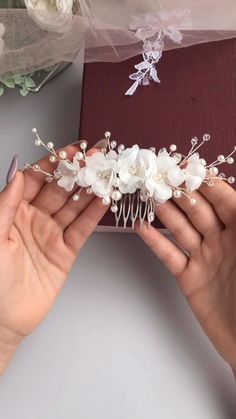 two hands are holding a white flower headpiece