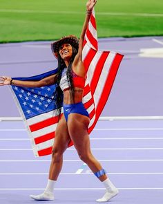 a woman holding an american flag on top of a track