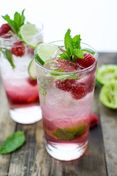 two glasses filled with raspberry mojitas and mint garnishes