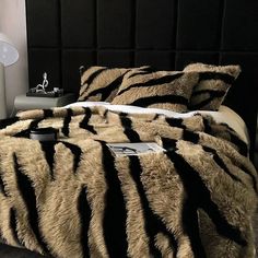 a bed with a black headboard and zebra print comforter