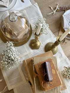 an open book sitting on top of a table next to candles and napkins with baby's breath