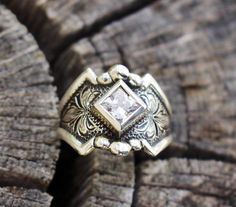 a close up of a ring on top of a piece of wood with a diamond in the center