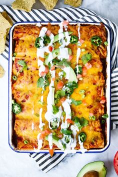 an enchilada dish with tortilla chips and avocado on the side