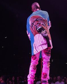 a man standing on top of a wooden pole in front of a crowd at a concert