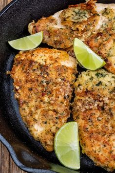 two pieces of chicken in a skillet with limes on the side and one slice cut out