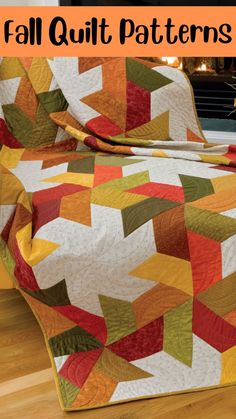 an orange and yellow quilt sitting on top of a wooden floor next to a fireplace