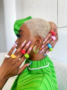 a woman with colorful nails on her face and hands over her head, wearing green dress