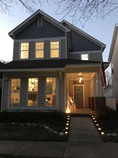 a house that is lit up at night with lights on the front and side windows