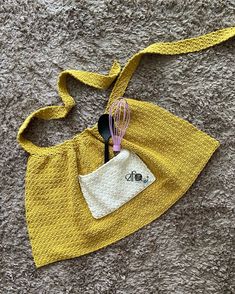 a yellow purse with a whisk in it on top of a carpeted floor