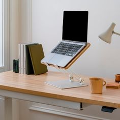 a laptop is sitting on a desk with books and a coffee cup next to it