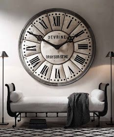 a large clock mounted to the side of a wall above a couch in a living room