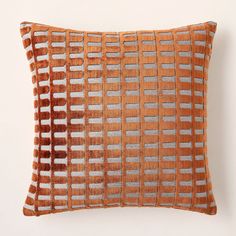 an orange and grey decorative pillow on a white wall