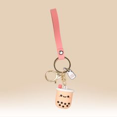 a keychain with a coffee cup on it is hanging from a pink strap