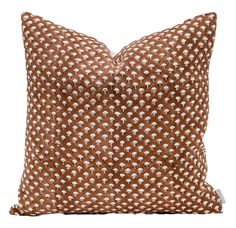 a brown and white pillow with small dots on the front, sitting on a white surface