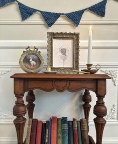 an old table with books and a candle on it in front of a blue bunting banner