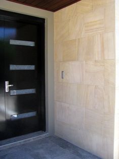 a black door is next to a white wall and concrete flooring in front of it