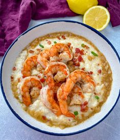 a bowl of shrimp and gritee with a lemon slice next to it on a table