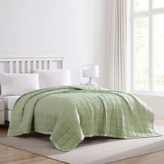 a bedroom with white walls and light green bedspread